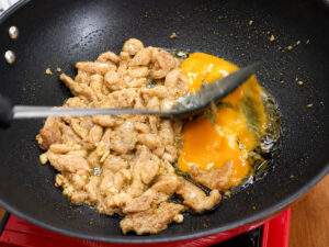 Poulet et œufs en cours de cuisson dans un wok pour préparer un Pad See Ew.