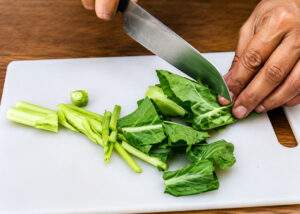 Découpe du brocoli chinois avant sa cuisson pour préparer un Pad See Ew traditionnel.