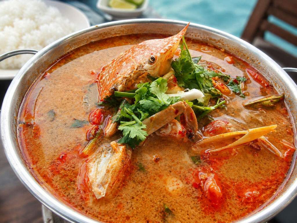 Soupe Tom Yam Nam Khon aux fruits de mer, crabe, citronnelle et coriandre servie dans un restaurant en bord de mer.