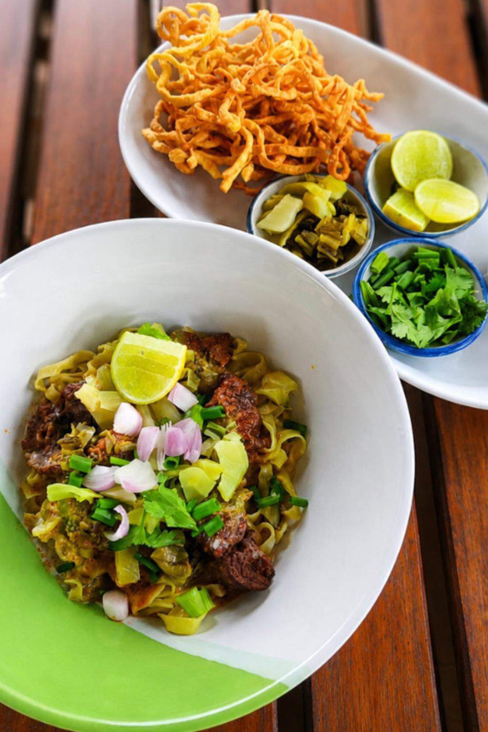 Khao Soi au bœuf avec nouilles croustillantes, citron vert, coriandre et légumes marinés