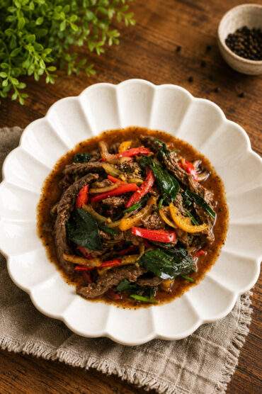 Bœuf au poivre noir thaï sauté au wok avec des poivrons rouges, des poivrons verts et du basilic thaï.