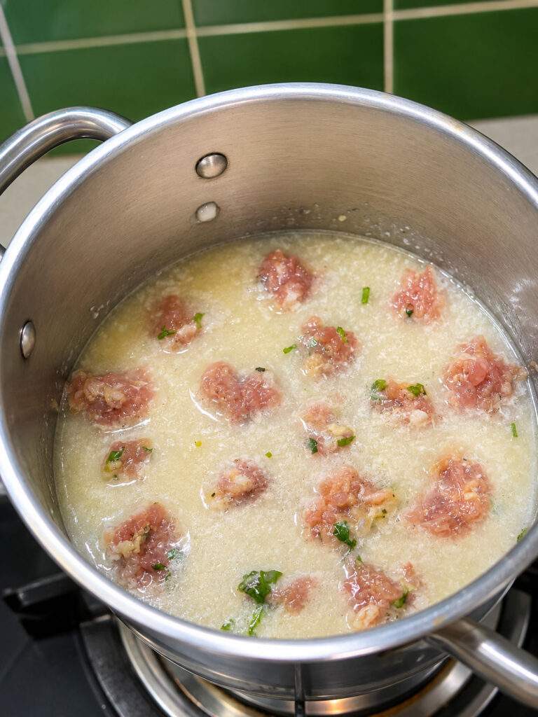 Boulettes de poulet en train de cuire dans la soupe de riz Khao Tom