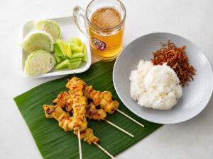 Brochettes de poulet thaïes servies avec du riz gluant et des légumes