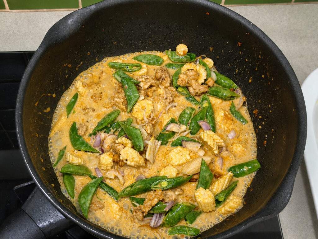 Sauce au curry jaune mijotant avec poulet, maïs nain et pois gourmands