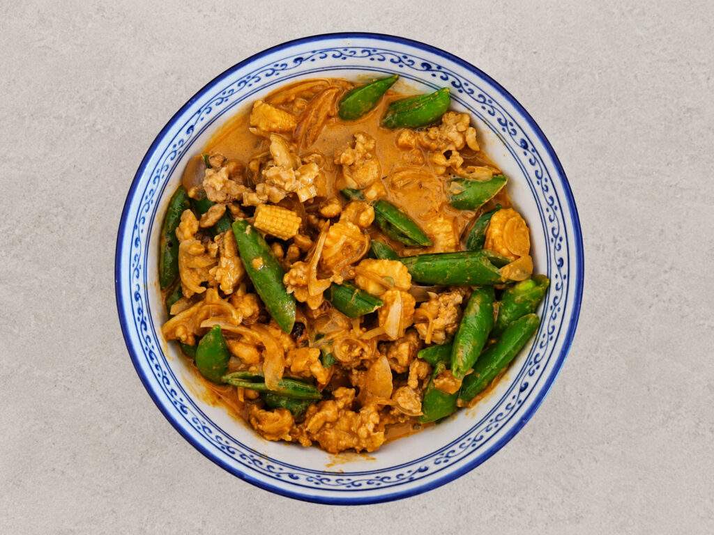 Curry jaune au poulet, pois gourmands et maïs nain dans un bol