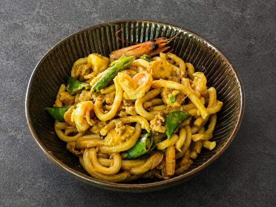 Nouilles udon au curry jaune avec poulet, crevettes et légumes croquants