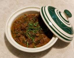 Bœuf rendang présenté dans une cocotte en céramique verte et blanche